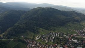 Aerial view around the villages Varnhalt, Steinbach and Neuweier in Germany. Early on a sunny morning in summer. Tilt down from the mountain to the village.