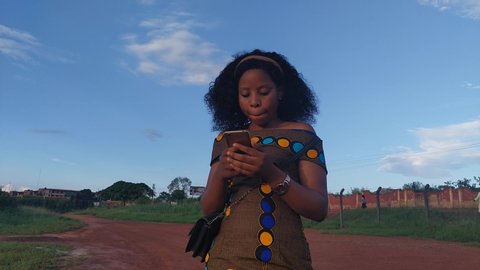 Pretty young african lady smiling and using her phone