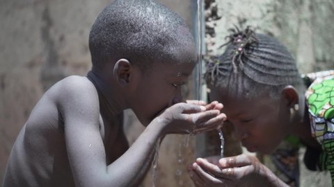 
Couple of Black African Children Drinking Water from tap, Human Rights, Poverty, Climate Change 