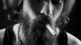 handsome tattooed and bearded smoking man. Hipster tattoed boy with cigarette. Black and white video clip