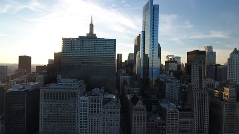 Chicago, USA: Downtown Chicago skyline aerial view from Millennium Park at sunset, drone shot flying backwards with lens flare