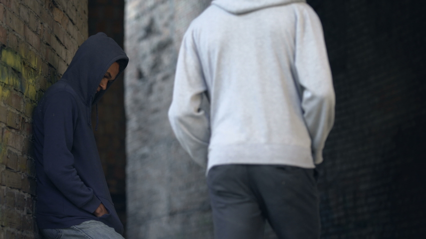 Male buying drug packet giving money in dangerous city area, illegal trafficking