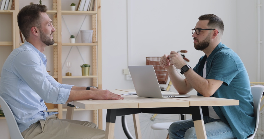 Two happy friendly businessmen talking laughing at office meeting sit at desk, smiling hr manager recruiter communicating with male applicant joking making good first impression during job interview Royalty-Free Stock Footage #1037298149