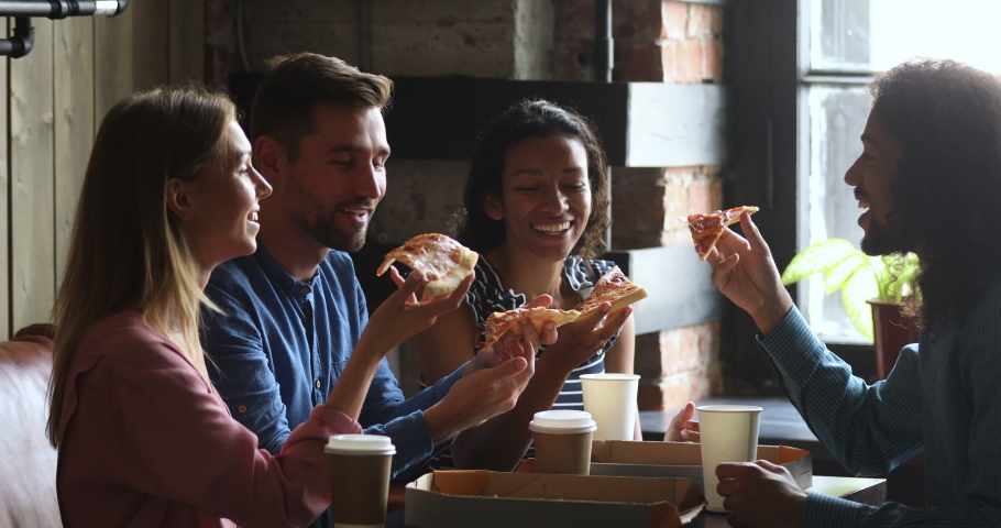 Happy multiracial business team people students laughing eating takeaway pizza together in cafe indoor, cheerful diverse staff friends group having fun share lunch food meal enjoy party sit at table Royalty-Free Stock Footage #1037298176