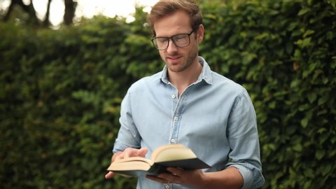 young casual smart man reading and turning pages of a book