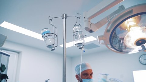 VINNITSA, UKRAINE - September 2019: Two chemotherapy bottles hanging from a tripod during operation in clinic. Medical equipment in the operating room.