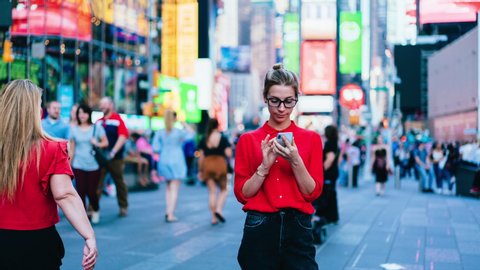Time lapse effect of millennial female blogger in trendy clothing standing at crowd square with cellular phone for networking on websites ignoring life going near prefer mobile communication