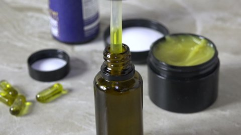 CBD oil drops falling slowly into a bottle with  hemp capsules and salve