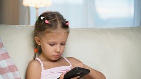 Little Girl Child Home On Sofa Playing On Smartphone
