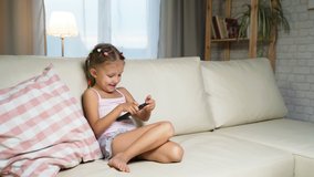 Little Girl Child Home On Sofa Playing On Smartphone