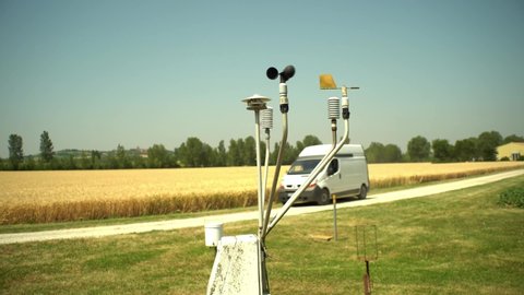 A Van Drives Past A Weather Station On A Farm.