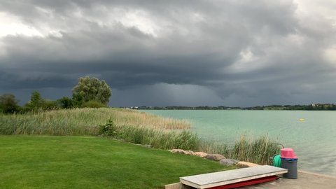 Thunderstorm approaching swiss lake. Shot in 4K at the Badi in Pfäffikon (Pfaeffikon) Zürich in Switzerland. Showing the lake and the diving board. Open swimming area.