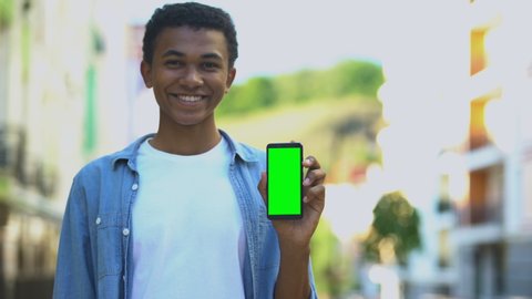 Smiling teenager holding smartphone with green screen, navigation application