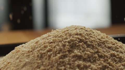 Breadcrumbs sprinkle onto the kitchen table. Slow motion video