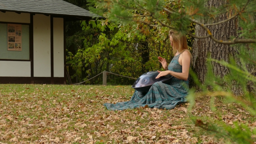 Girl rehearses playing modern percussion musical instrument outdoors