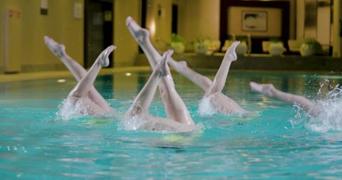 Water team sports, female swimmers performing, synchronized swimming, view of the legs.