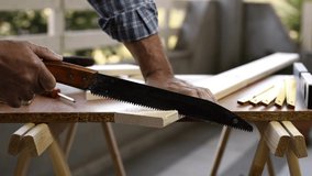 Adult craftsman carpenter with manual saw working on cutting a wooden table. Housework do it yourself. Footage.