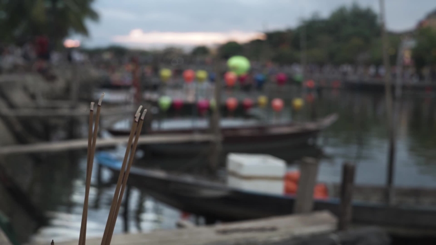 Burning Incense, selected focus with background out focus. Sunset landscape with lanterns and boats moored at Hoi An.