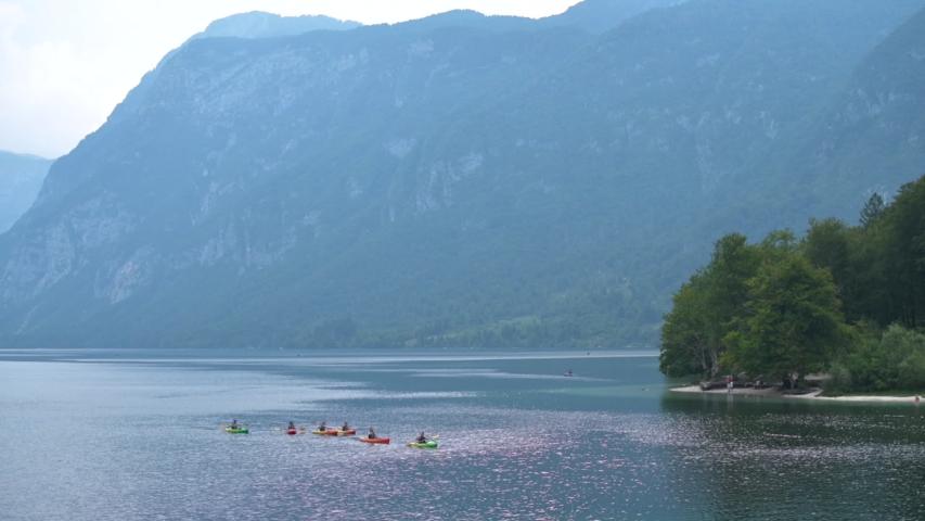 Canoers rowing canoe boats on Lake Bohinj in summer. Group of unrecognizable canoeist enjoying active holiday vacation outdoor activity on water