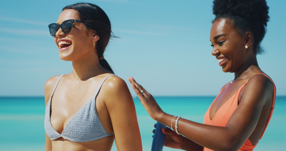 Slow motion of happy young different ethnicity girlfriends are having fun to apply a sunscreen or sun tanning lotion to take care of their skin during a vacation on a beach. Royalty-Free Stock Footage #1037350160
