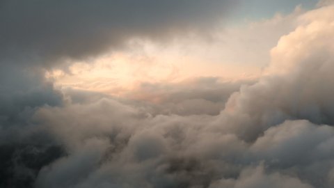 Aerial view flying through cumulus thunderclouds at sunset. Gold colored sunset cloudiness in high contrast. Real sky. The concept of dreams and weather forecast