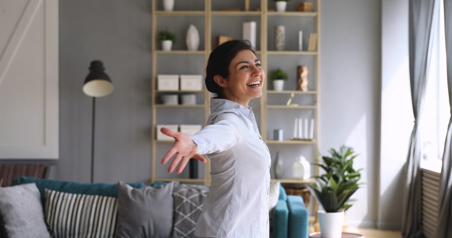 Happy overjoyed first time home owner young indian woman spin dance alone with arms outstretched in modern living room interior enjoy freedom having fun in new flat, investment, independence concept Royalty-Free Stock Footage #1037352899