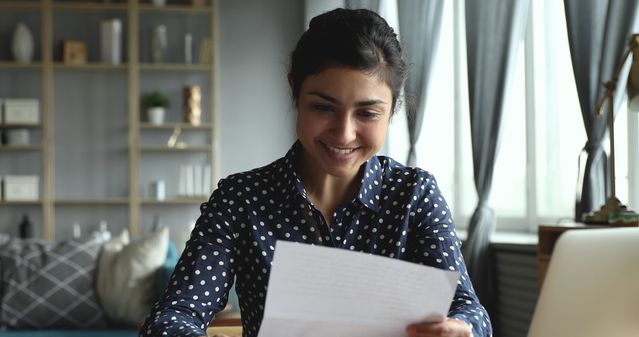 Excited overjoyed indian girl student open envelope reading good news in paper admission letter at home, happy euphoric young woman holding mail notice celebrate loan approval get new job scholarship | Shutterstock HD Video #1037352926