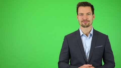 A young handsome businessman talks to the camera with a smile - green screen studio