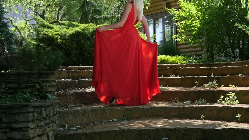 Blonde young girl in red dress posing in a green park location