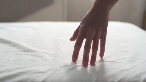 Slow motion follow close up shot of woman dragging her hand on clean white bed gently. Can use for comfort, soft, relax concept.