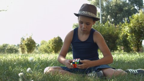Kyiv, Ukraine - Jule 20, 2019: Boy solving Rubik's Cube. Smart child focused on solving interesting puzzle game. Rubik's Cube is a 3D combination puzzle invented in 1974