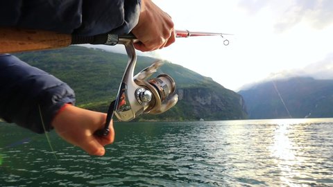Woman fishing on Fishing rod spinning in Norway. Fishing in Norway is a way to embrace the local lifestyle. Countless lakes and rivers and an extensive coastline means outstanding opportunities...