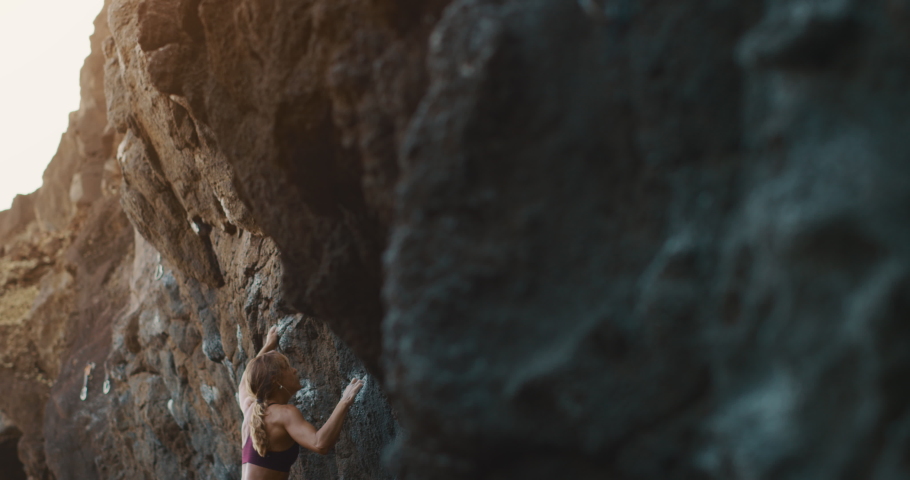 Young fit woman lead rock climbing on sport route in golden light, outdoors rock climbing, cinematic slow motion rock climbing moments