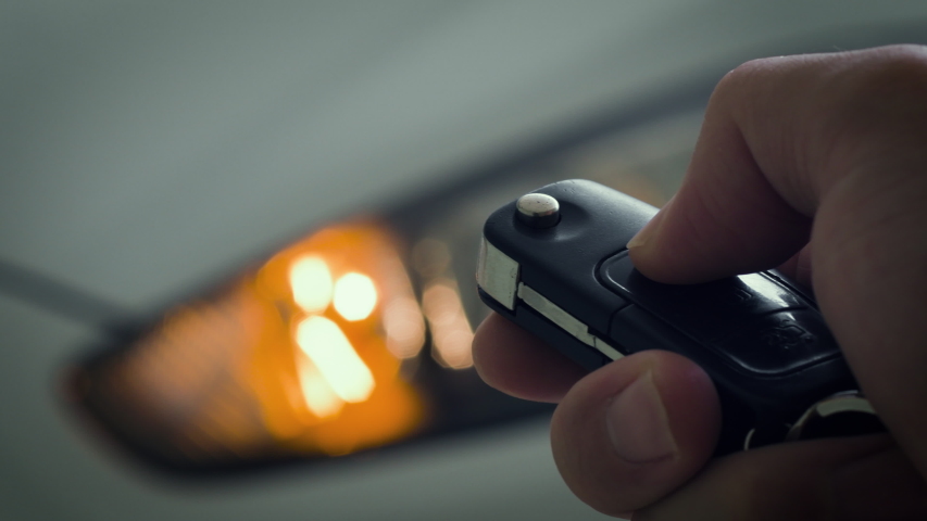 Locking and unlocking the car by the car's key remote control. Pressing the button of the car key and the lights of the car blink when it's open or closed. Royalty-Free Stock Footage #1037382239