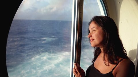 woman Watching Sunset From cabin window On Luxury Cruise Ship
