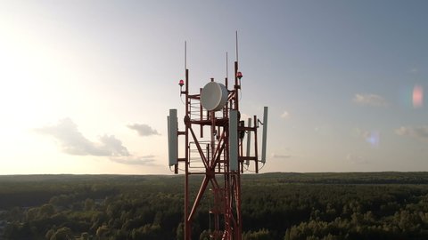 Closeup aerial shot around of telecommunication tower in a rural location. Telecom tower antennas and satellite transmits the signals of cellular 5g 4g mobile signals to the consumers and smartphones.