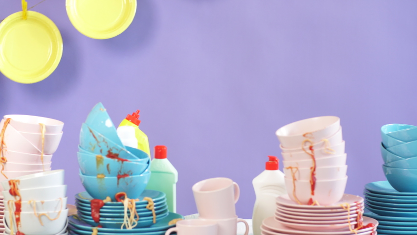 Emotional helpless woman in panic, depressed with washing process, sits behind the table full of unwashed plates and cups