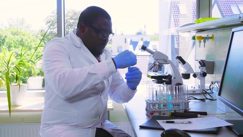 African-american scientist working in lab. Male doctor making microbiology research. Biotechnology, chemistry, bacteriology, virology, dna and health care.