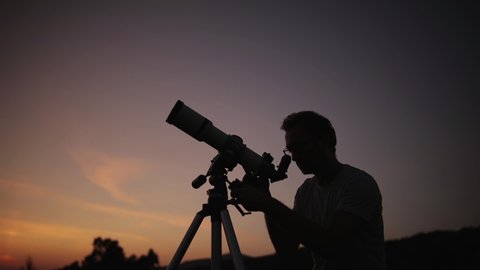 Astronomer with a telescope watching at the stars and Moon. 
