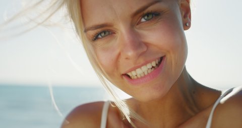 Slow motion of young smiling blond hair woman is happy to enjoy a summer vacation on a beach with a sea in a sunny day.