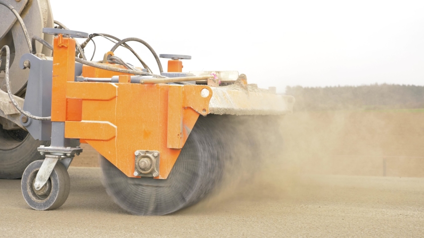 Last part of fully mechanised process of concrete road constuction. A roller with hard brushes sweeps the top of the concrete road.