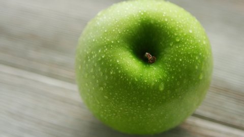 Closeup shot of green wet apple placed on light wooden background