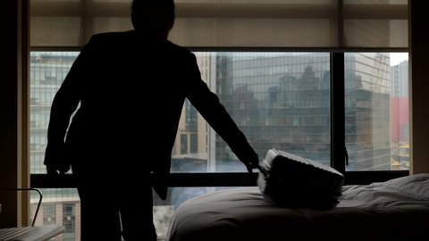 Business man check out from hotel room. Traveller take suitcase from bed and go away, super slow motion shot. Window curtain slowly move down.