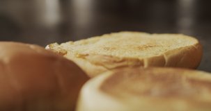 Macro shot of tweezers chef puts piece of butter on bun to burger. Slow motion video 4K