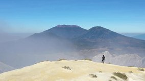 Aerial view dolly zoom clip of a traveler standing on the edge of a cliff at Mount Ijen volcano