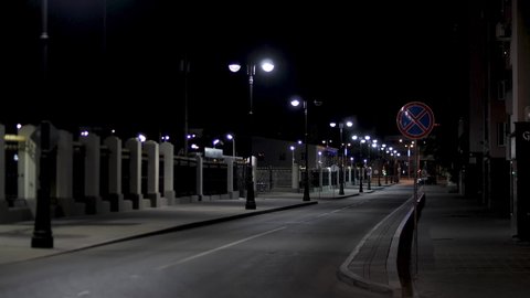 Empty urban street, night scenery in the city with street lamps on black sky background. Stock footage. Late evening road in modern residential area.