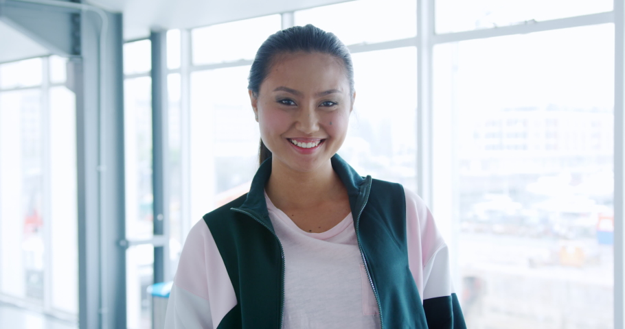 Front view close up of a young Asian female creative smiling to camera in a modern office | Shutterstock HD Video #1037429054