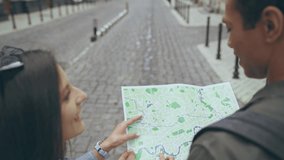 back view of couple with map walking on street