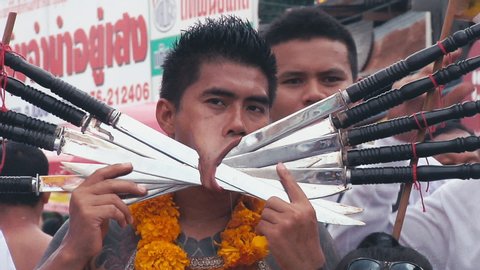 phuket / Thailand - 10 19 2014: Adult Male Standing with his mouth pierced with large knives in Vegetarian Festival at Phuket, Thailand