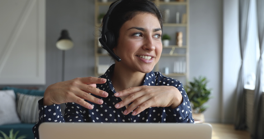 Happy indian young woman wear headset communicating by conference call speak looking at computer at home office, video chat job interview or distance language course class with online teacher concept Royalty-Free Stock Footage #1037437004
